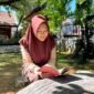 Siswi SMAN 1 Pamekasan Sabrina Yasmin Firyal Siswanto sedang membaca buku di halaman sekolah (LAILIYATUN NURIYAH/KLIK MADURA).
