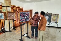 BH. Riyanto menjelaskan makna dan filosofi salah satu lukisan kepada Pemred Klik Madira, Prengki Wirananda di Hotel Odaita, Pamekasan. (ISTIMEWA)