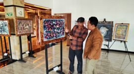 BH. Riyanto menjelaskan makna dan filosofi salah satu lukisan kepada Pemred Klik Madira, Prengki Wirananda di Hotel Odaita, Pamekasan. (ISTIMEWA)