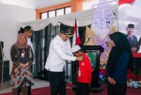 Bupati Sampang H. Slamet Junaidi saat mengalungkan tanda peserta MPLS Sekolah Rakyat Terintegerasi 1 Sampang. (KLIKMADURA)