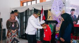 Bupati Sampang H. Slamet Junaidi saat mengalungkan tanda peserta MPLS Sekolah Rakyat Terintegerasi 1 Sampang. (KLIKMADURA)