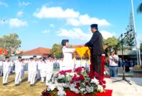 Kepala SMAN 2 Pamekasan Moh. Arifin menyerahkan bendera merah putih kepada pengibar bendera dalam rangka upacara memperingati HUT ke-81 Kemerdekaan Republik Indonesia. (LAILIYATUN NURIYAH / KLIKMADURA)