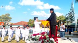 Kepala SMAN 2 Pamekasan Moh. Arifin menyerahkan bendera merah putih kepada pengibar bendera dalam rangka upacara memperingati HUT ke-81 Kemerdekaan Republik Indonesia. (LAILIYATUN NURIYAH / KLIKMADURA)