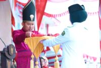 Bupati Sumenep Dr. Achmad Fauzi Wongsojudo menyerahkan sang saka merah putih kepada petugas pengibar bendera. (KLIKMADURA)