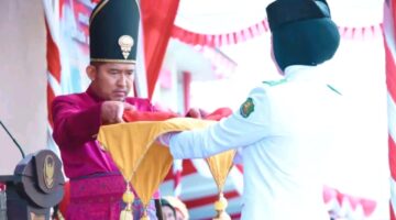 Bupati Sumenep Dr. Achmad Fauzi Wongsojudo menyerahkan sang saka merah putih kepada petugas pengibar bendera. (KLIKMADURA)