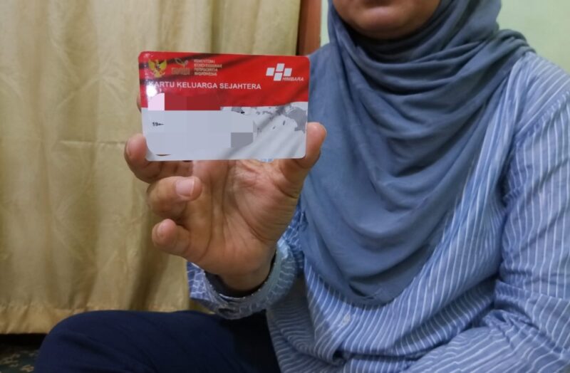 Salah satu warga menunjukkan kartu PKH. (ALI MUCHTAR / KLIKMADURA)