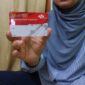 Salah satu warga menunjukkan kartu PKH. (ALI MUCHTAR / KLIKMADURA)