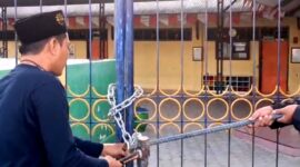 Ketua PD Muhammadiyah Pamekasan Azis Ashari membuka paksa gerbang TK ABA IV Pamekasan yang disegel ahli waris tanah. (ISTIMEWA).