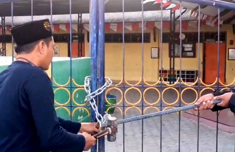 Ketua PD Muhammadiyah Pamekasan Azis Ashari membuka paksa gerbang TK ABA IV Pamekasan yang disegel ahli waris tanah. (ISTIMEWA).