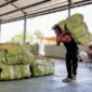 Salah satu warga tengah memikul satu bal tembaku di salah satu gudang di Pamekasan. (MOH. IQBALUL KHAVEI MZ / KLIKMADURA)