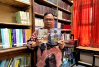 Dosen Sastra Prodi Pendidikan Bahasa Indonesia, Unira, Muhammad Tauhed Supratman memegang buku karyanya berjudul Lukamu Abadi dan buku Kumpulan Puisi Ranjang Poskolonial karya Royyan Julian di Perpustakaan Unira, Senin (12/10/2026) (LAILIYATUN NURIYAH/KLIK MADURA).