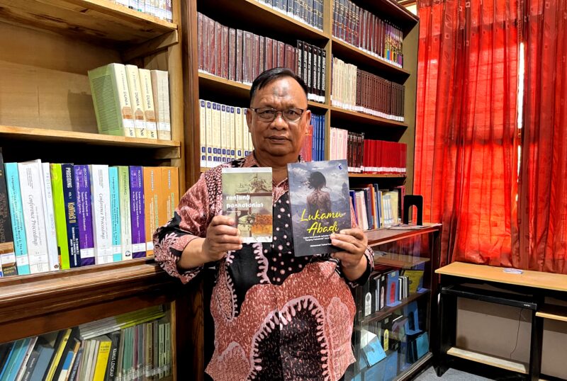 Dosen Sastra Prodi Pendidikan Bahasa Indonesia, Unira, Muhammad Tauhed Supratman memegang buku karyanya berjudul Lukamu Abadi dan buku Kumpulan Puisi Ranjang Poskolonial karya Royyan Julian di Perpustakaan Unira, Senin (12/10/2026) (LAILIYATUN NURIYAH/KLIK MADURA).