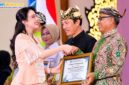 Kepala Disdikbud Pamekasan Basri Yulianto menerima penghargaan dari Balai Bahasa Provinsi Jawa Timur yang diwakili TP PKK Provinsi Jawa Timur, Arumi Bachsin Emil Dardak, Rabu (21/10/2026). (ISTIMEWA)