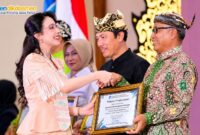 Kepala Disdikbud Pamekasan Basri Yulianto menerima penghargaan dari Balai Bahasa Provinsi Jawa Timur yang diwakili TP PKK Provinsi Jawa Timur, Arumi Bachsin Emil Dardak, Rabu (21/10/2026). (ISTIMEWA)