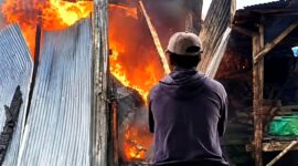 Salah satu warga berupaya memadamkan api yang melalap lapak di Pasar Tambelangan, Sampang. (KLIKMADURA)