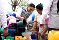 Manager PLN UP3 Madura, Radea Cakrawala Nusantara menuangkan air bersih ke wadah milik warga. (KLIKMADURA)
