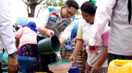 Manager PLN UP3 Madura, Radea Cakrawala Nusantara menuangkan air bersih ke wadah milik warga. (KLIKMADURA)