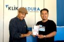 Sastrawan BH. Riyanto menyerahkan buku puisi hasil karyanya kepada Pemred Klik Madura, Prengki Wirananda. (IMDAD FAIHA ILA SABILA / KLIKMADURA)