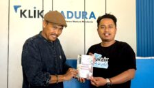 Sastrawan BH. Riyanto menyerahkan buku puisi hasil karyanya kepada Pemred Klik Madura, Prengki Wirananda. (IMDAD FAIHA ILA SABILA / KLIKMADURA)