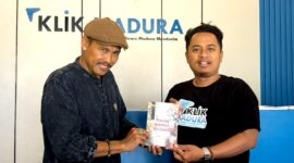 Sastrawan BH. Riyanto menyerahkan buku puisi hasil karyanya kepada Pemred Klik Madura, Prengki Wirananda. (IMDAD FAIHA ILA SABILA / KLIKMADURA)