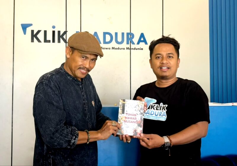 Sastrawan BH. Riyanto menyerahkan buku puisi hasil karyanya kepada Pemred Klik Madura, Prengki Wirananda. (IMDAD FAIHA ILA SABILA / KLIKMADURA)