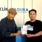 Sastrawan BH. Riyanto menyerahkan buku puisi hasil karyanya kepada Pemred Klik Madura, Prengki Wirananda. (IMDAD FAIHA ILA SABILA / KLIKMADURA)